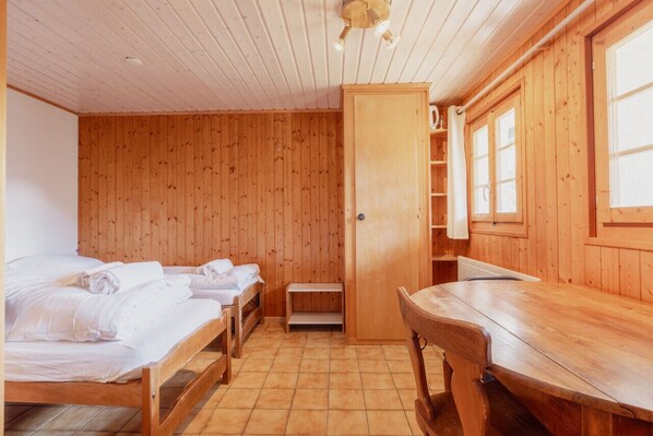 Een houten kamer met twee bedden, een houten tafel en een kledingkast.