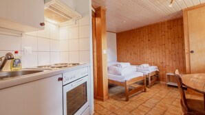 Une cuisine compacte équipée d’une cuisinière, d’un évier et d’un petit coin repas avec une table et des chaises.