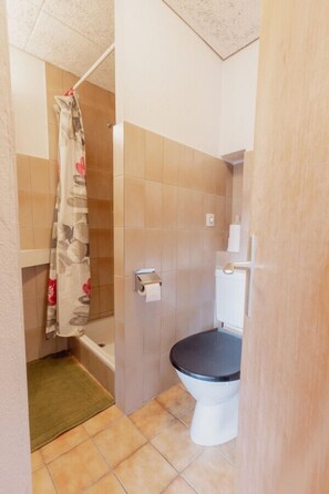 Een badkamer met toilet, douchegordijn en handdoekhouder.