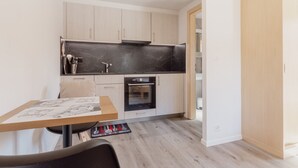 Una cocina compacta con armarios de madera clara, encimera de mármol negro y horno integrado.