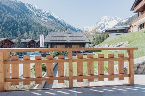 A wooden fence with a view of a mountain and a building with a sign that reads 'INTERSPORT'. - Studio à 2 Minutes des Remontées Mécaniques (Grimentz)