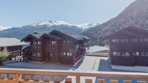 Un edificio de estilo chalet de madera con balcón, frente a montañas nevadas.