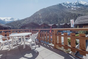 Une terrasse en bois avec des sièges extérieurs, offrant une vue sur un paysage montagneux.