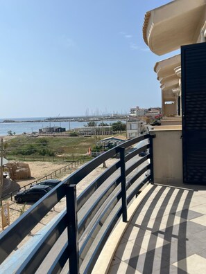 A balcony with a view of the sea and boats, a tiled floor, and a metal railing. - One Bedroom Apartment   Sea Side (Marzamemi)