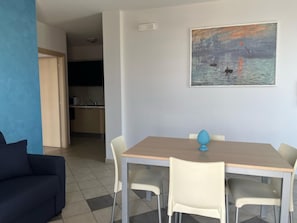A dining area with a table, chairs, a painting, and a sofa.