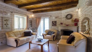 Ein gemütliches Wohnzimmer mit Steinwand, Holzbalken, Kamin und Ledermöbeln.