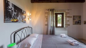 Ein Schlafzimmer mit Bett, einem Fenster mit Vorhängen, einer Heizung sowie Wanddekorationen, darunter eine Stadtansicht und ein Oldtimer.