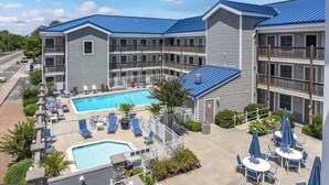 A multi-story hotel with a swimming pool, outdoor seating, and a fenced patio area.