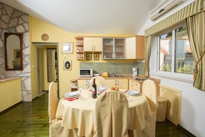 Un comedor con una mesa dispuesta para cuatro personas, un microondas y un lavamanos en la cocina.
