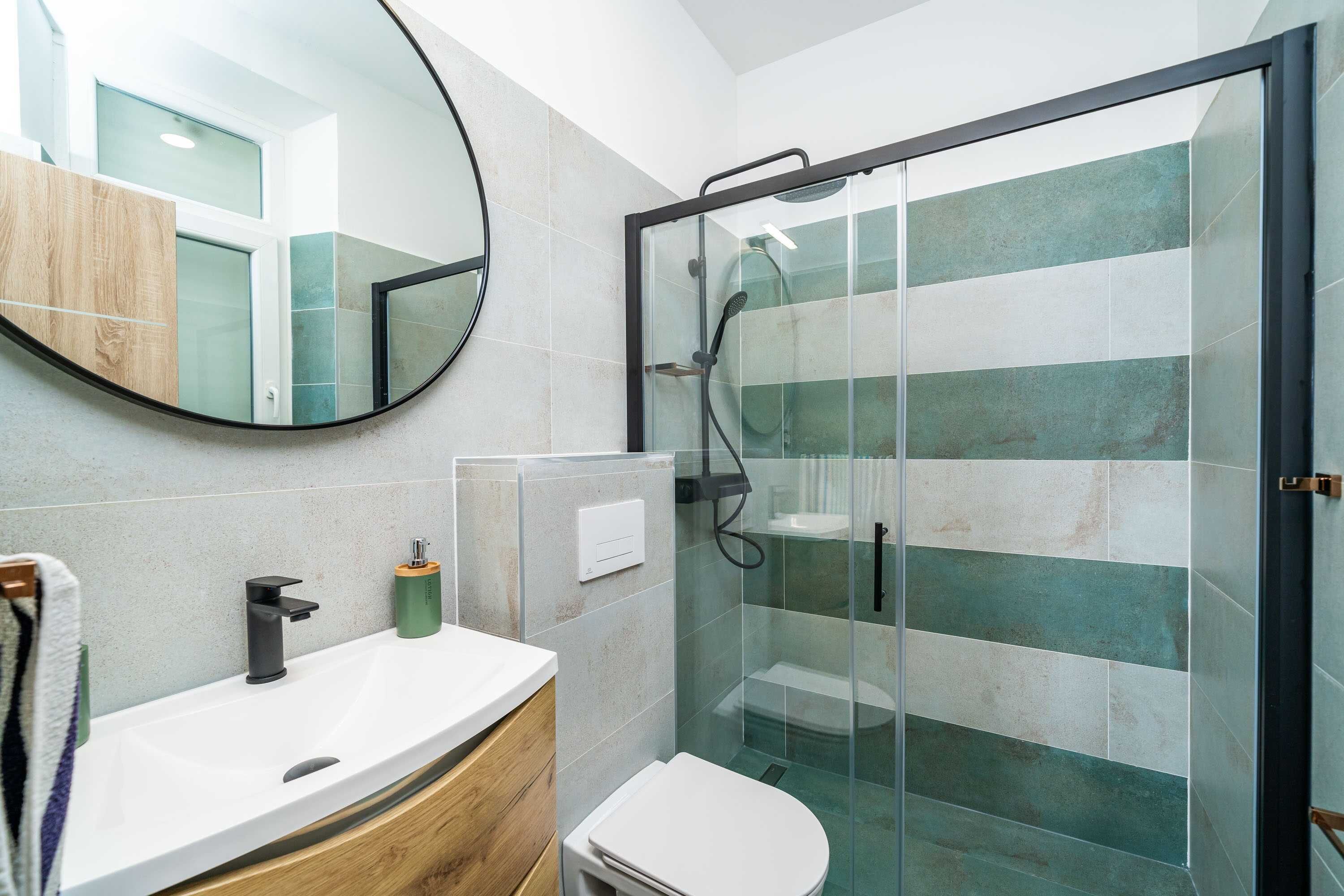 Een moderne badkamer met een douchecabine van glas, een witte wastafel en een houten wastafelmeubel.