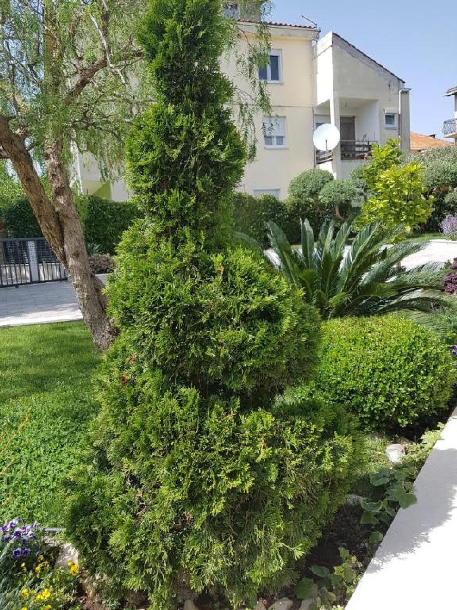 Un immeuble d’habitation doté d’un balcon, entouré de jardins et d’arbres bien entretenus.