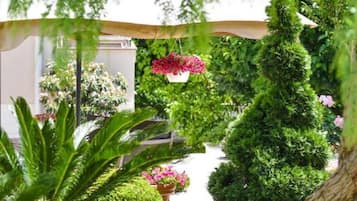 A well-maintained garden with various plants and flowers, a pathway, and a building in the background.