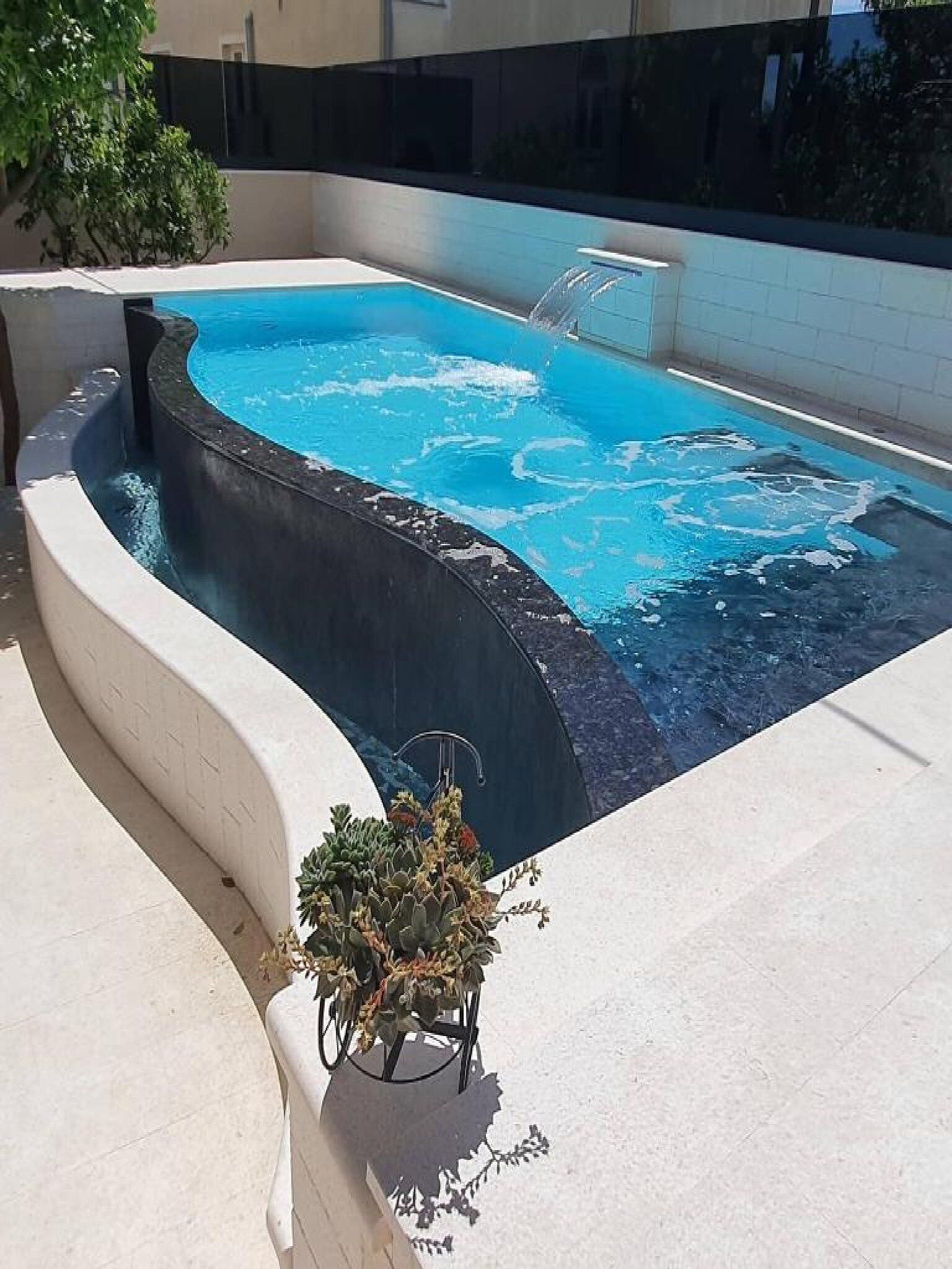 A swimming pool with a curved edge and a built-in jacuzzi.