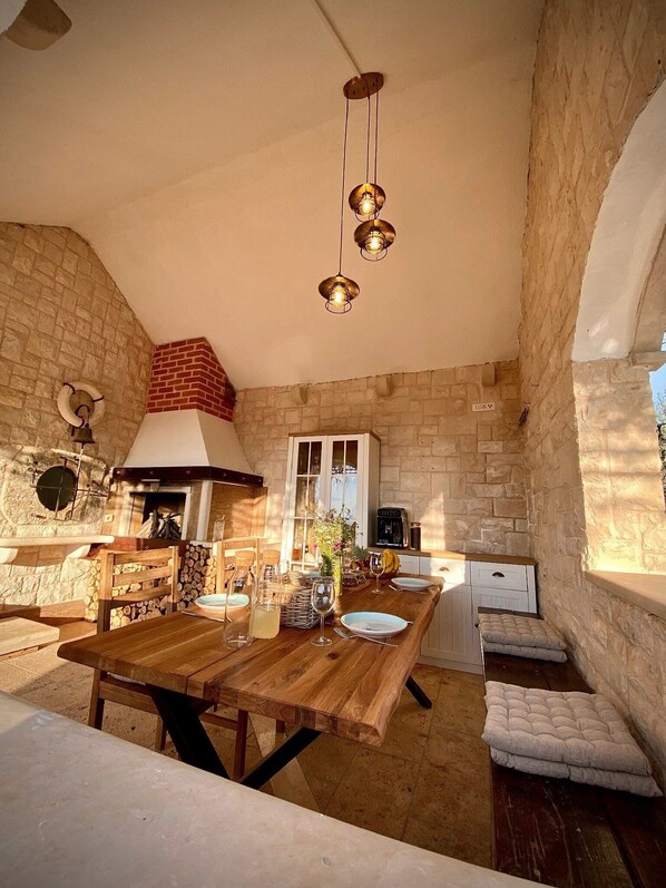 Une cuisine rustique avec un mur en pierre, une table en bois et des luminaires suspendus.