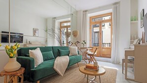 Una sala moderna con un sofá verde, una mesita redonda y un espejo grande.