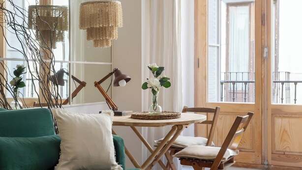 Una sala acogedora con un sofá verde, una mesa de comedor de madera y una estantería.
