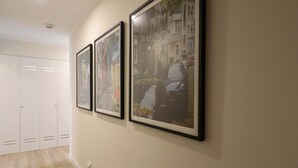 A hallway with three framed pictures on the wall, a white closet with sliding doors, and a light-colored wooden floor. - w * | Splendid 1BR in the Heart of Barranco (Lima)
