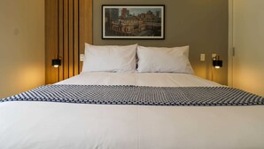 A neatly made bed with a patterned bedspread, two white pillows, and a framed cityscape picture on the wall. - w * | Splendid 1BR in the Heart of Barranco (Lima)