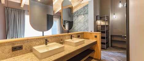 Un baño moderno con dos lavamanos, espejos grandes, vigas de techo de madera y un suelo con estampado de espiga.