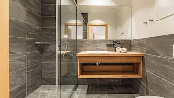 Ein modernes Badezimmer mit einer gläsernen Duschkabine, einem Holzbadezimmermöbel und einem großen Spiegel.