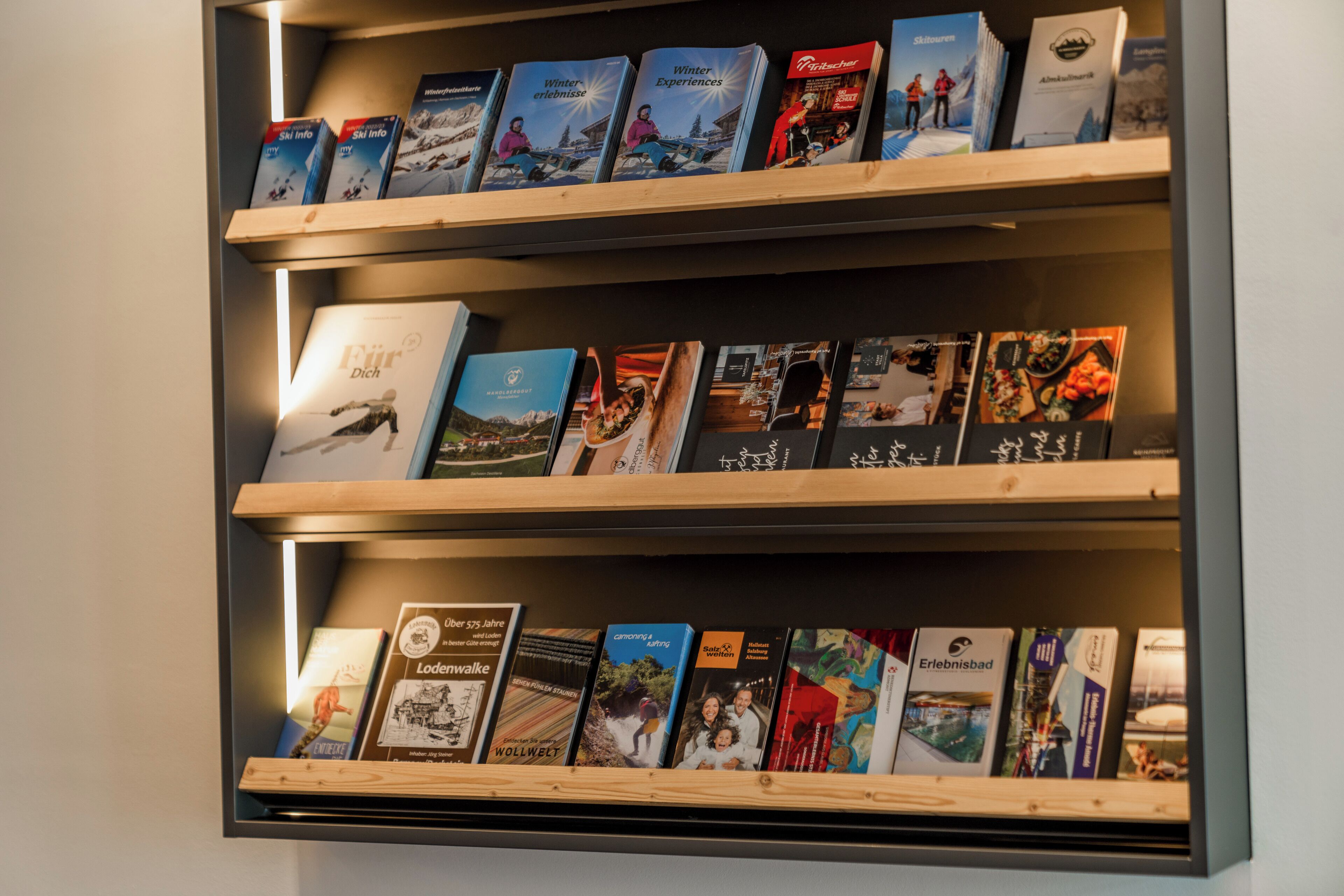 En vægmonteret hylde med rejsebøger og brochurer.