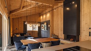 A modern kitchen with wooden walls, a large dining table, and pendant lighting.