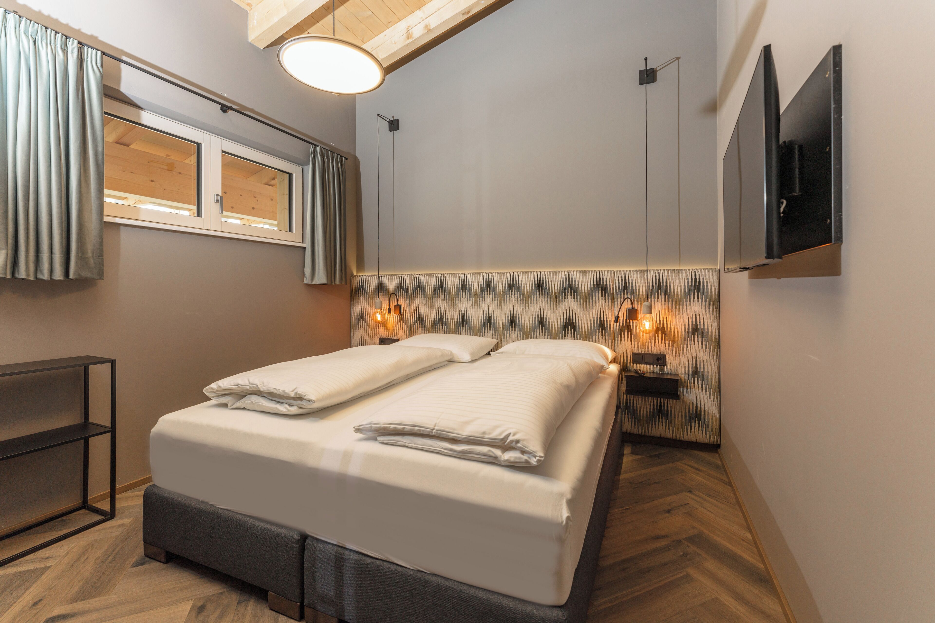 Una habitación de hotel moderna con una cama, un televisor, un estante y una pared con diseño.