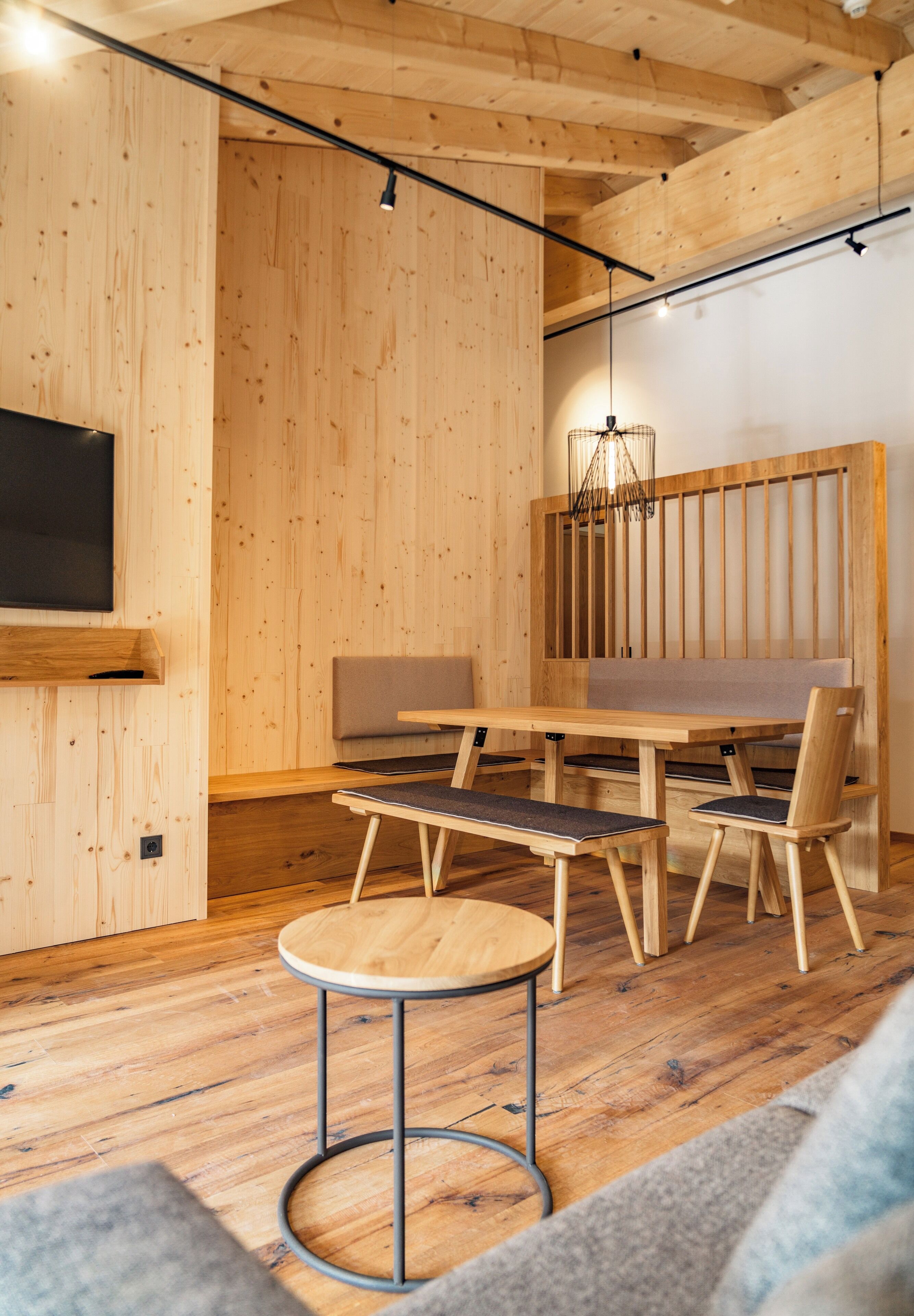 Un interior moderno con paredes de madera, una mesa de comedor, sillas, un banco y una mesa redonda.