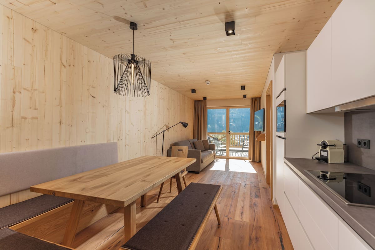 A wooden interior with a dining area, sofa, and kitchen.