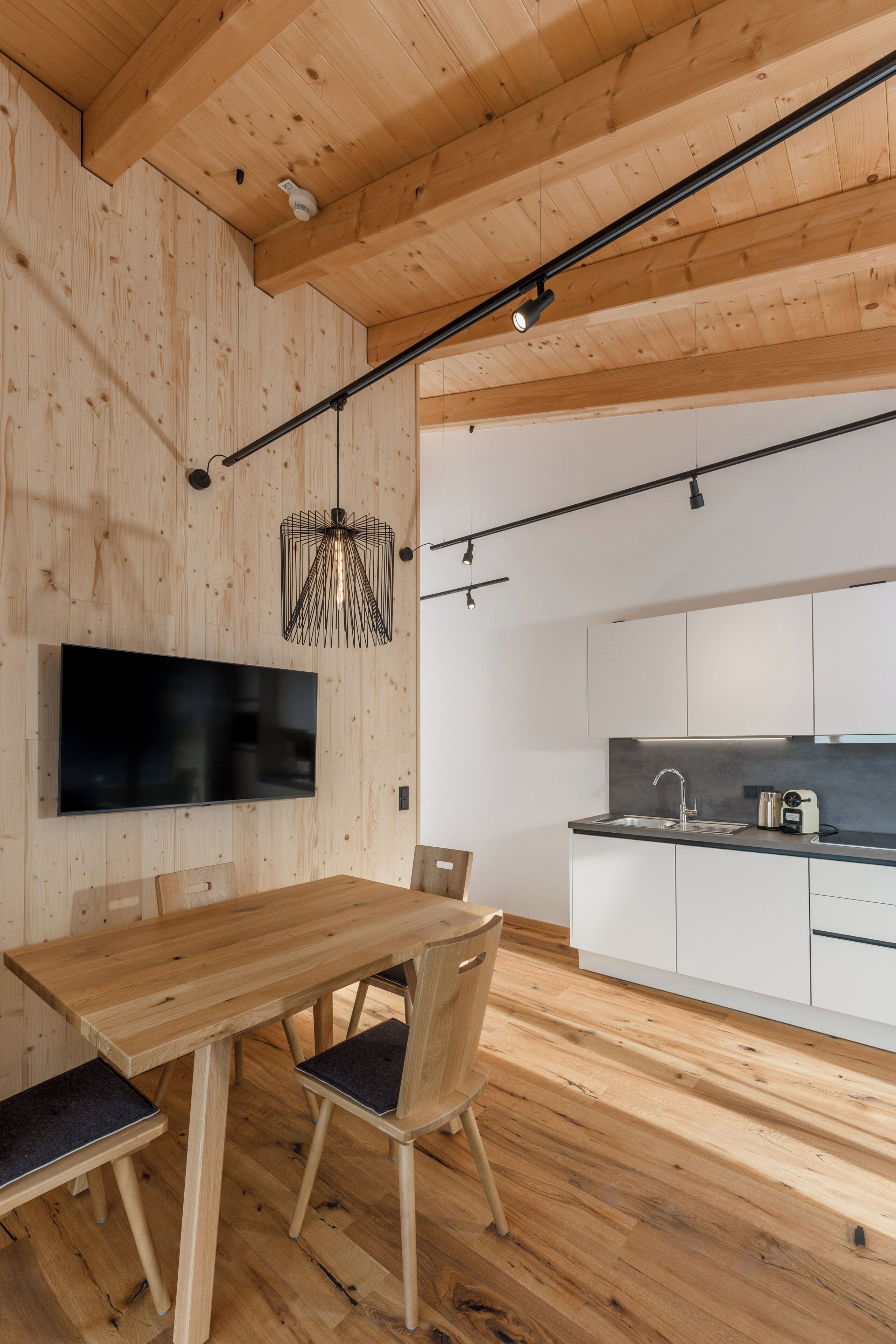 A modern kitchen with white cabinets, a black countertop, and a stainless steel sink.