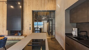 A modern kitchen with a central island, wooden walls, and a built-in stove.