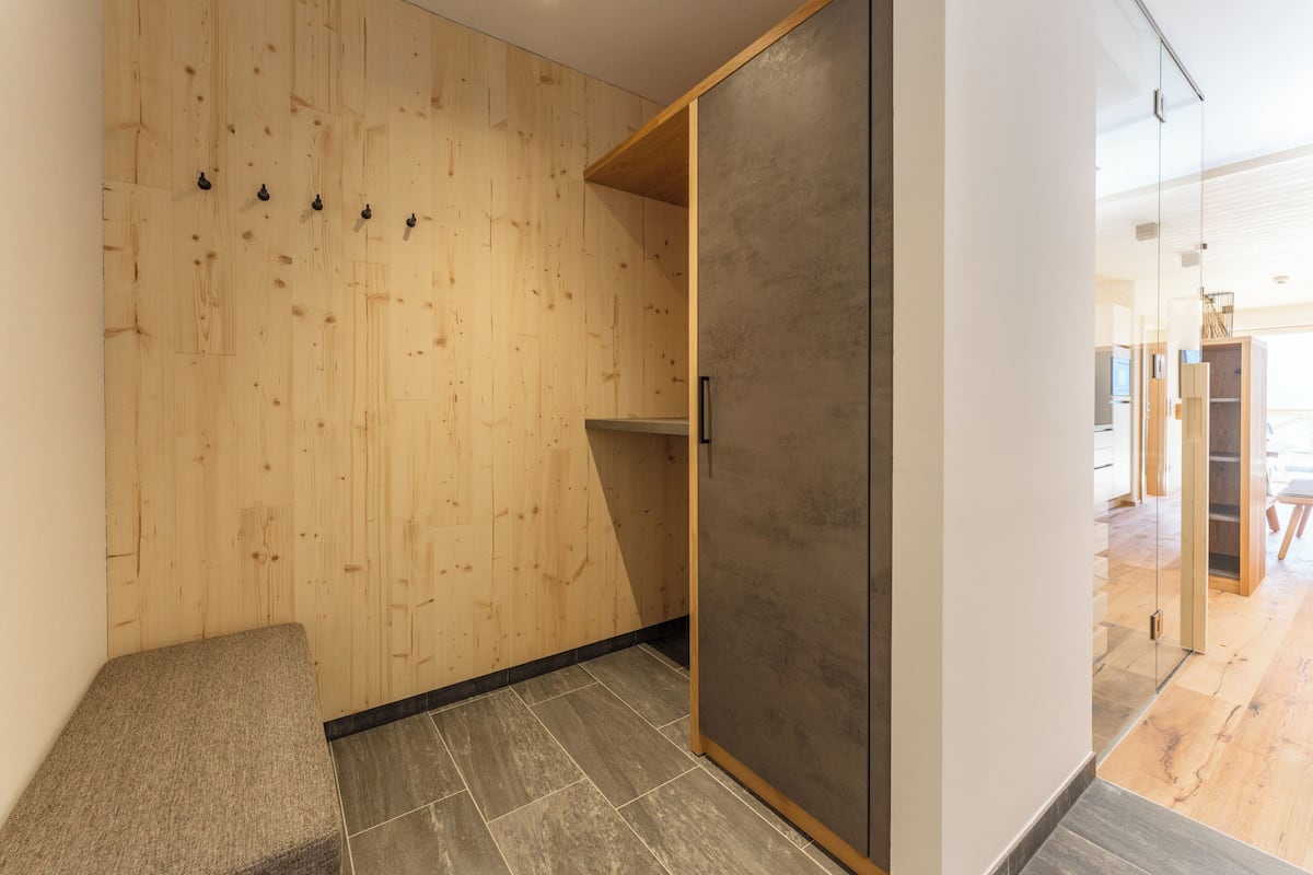 A modern interior with a wooden wall, a grey door, and a bench.
