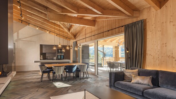 A modern interior with a wooden ceiling, a dining area, a sofa, and a kitchen.