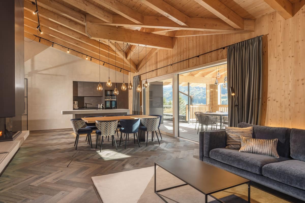 A modern interior with a wooden ceiling, a dining area, a sofa, and a kitchen.