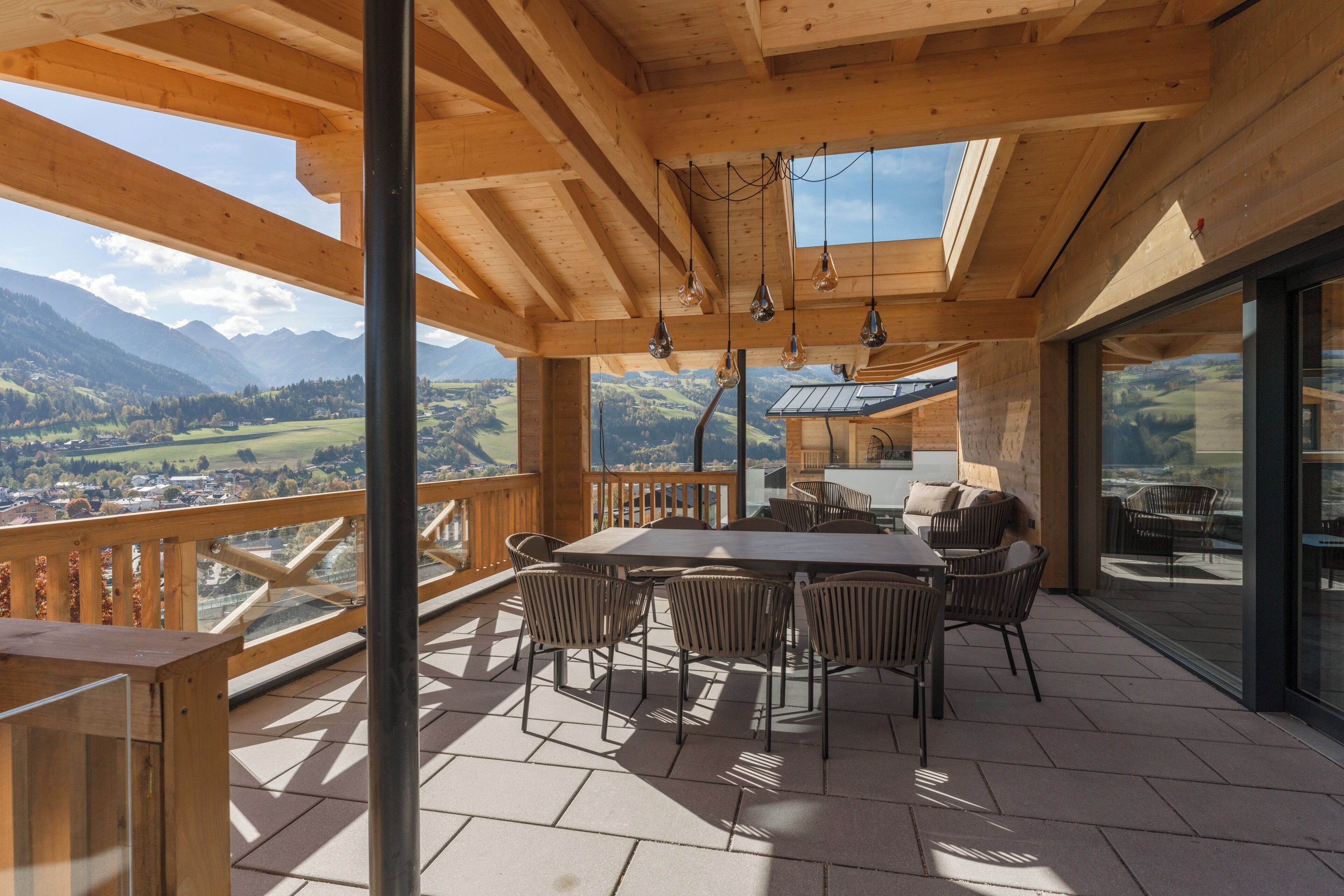 A wooden deck with a table and chairs, overlooking a mountainous landscape.