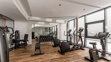 A modern gym with cardio equipment, weight machines, and a mirror wall.