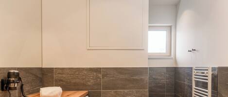 Un baño moderno con lavadora integrada, tocador de madera, espejo grande y perchero.
