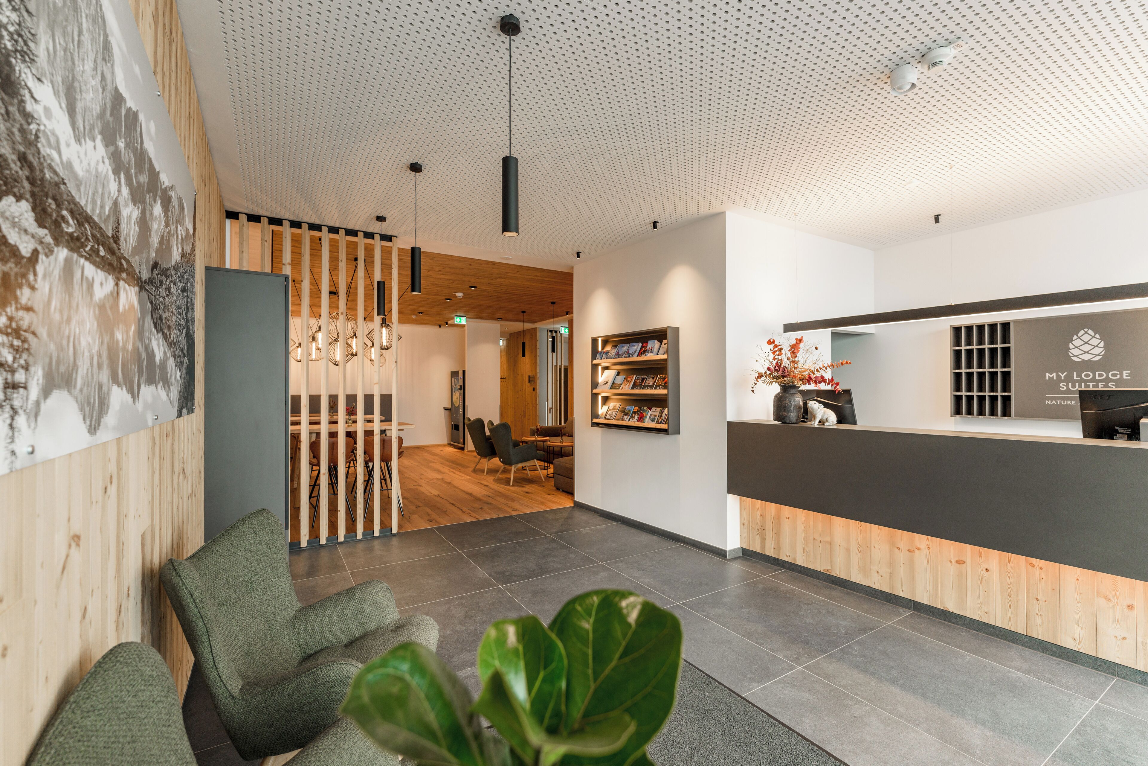 A reception area with a wooden reception desk, a seating area with chairs, and a wall-mounted bookshelf.