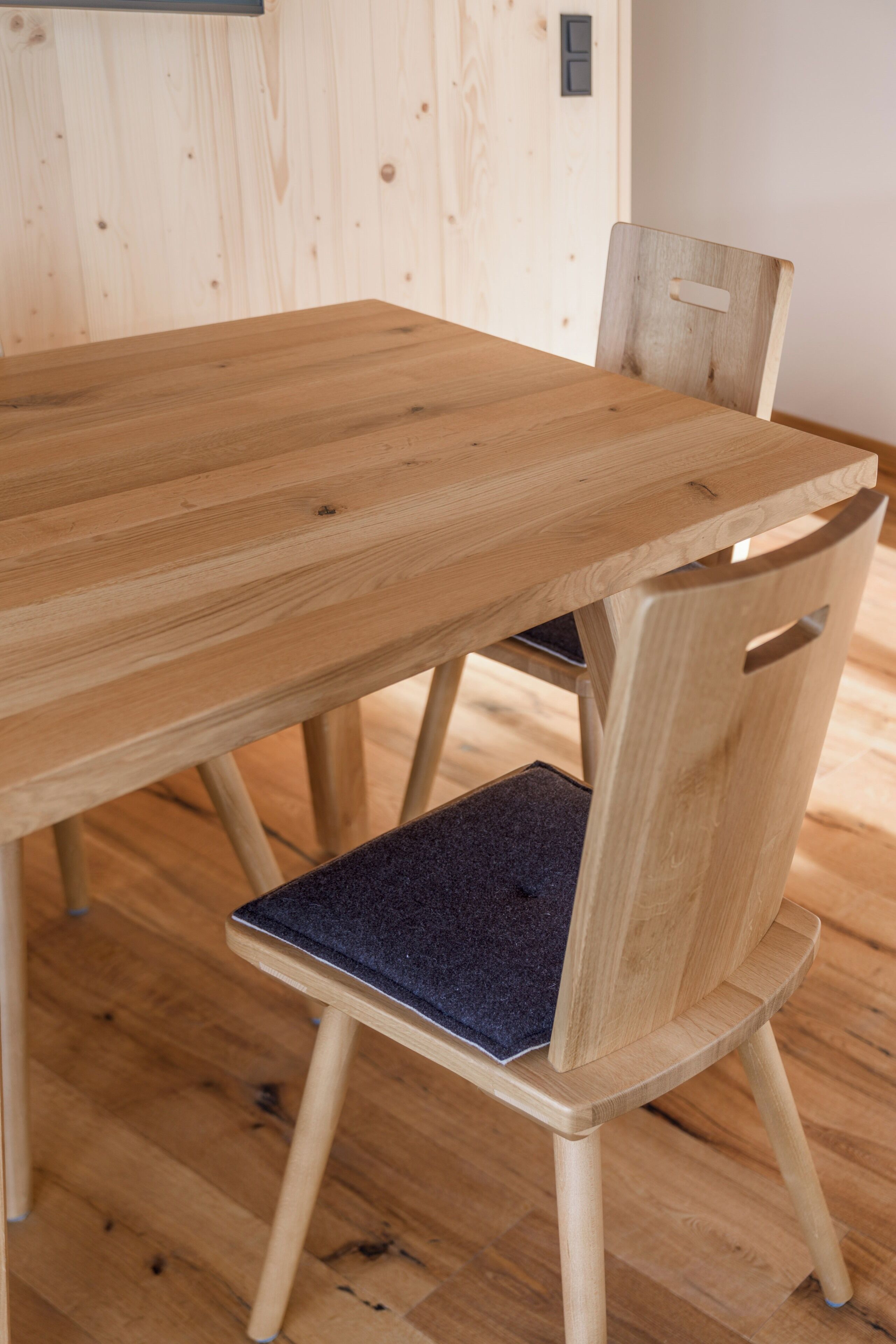 Una mesa de comedor de madera con una silla que tiene un cojín oscuro en el asiento.