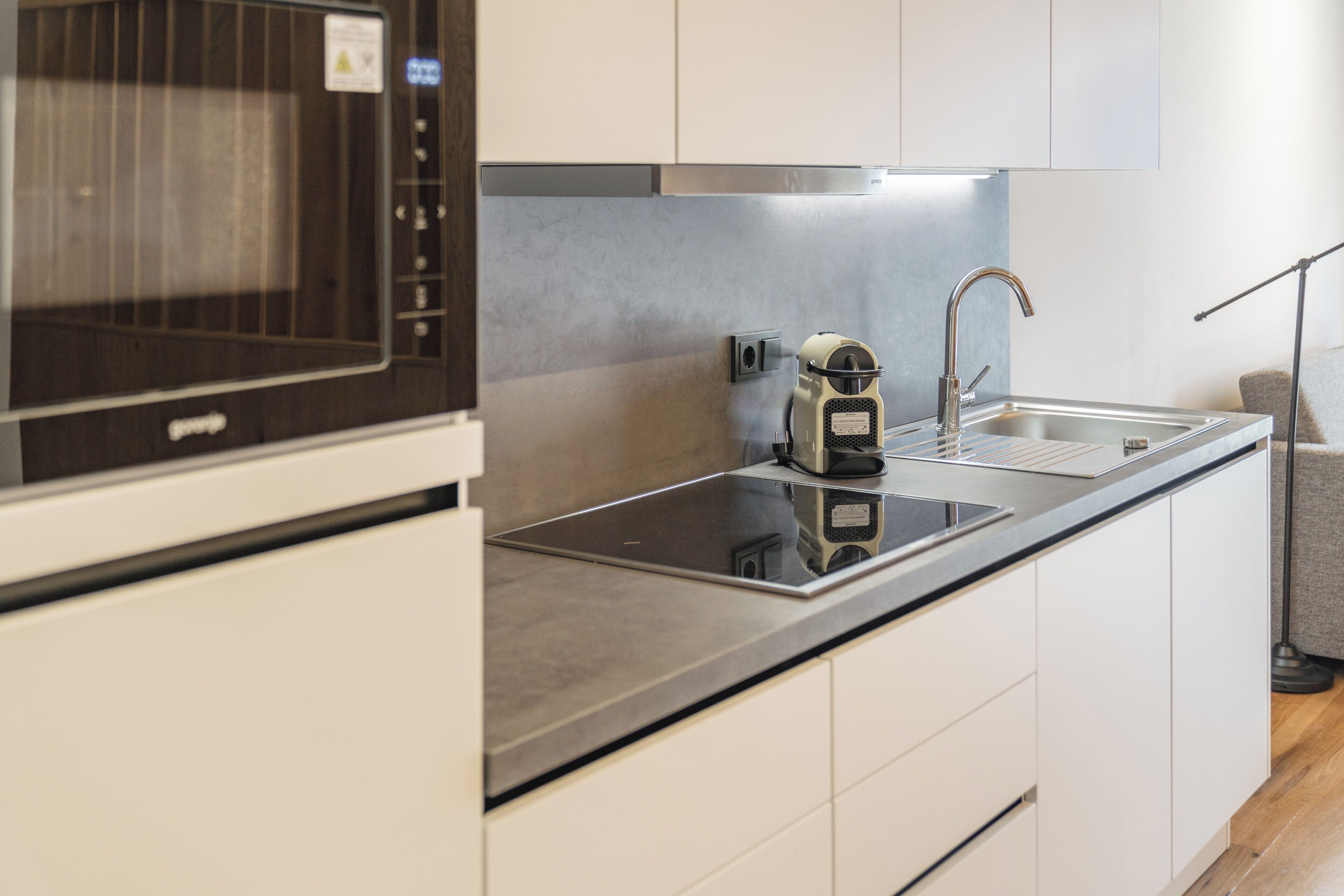 A modern kitchen with a built-in microwave, a stainless steel sink, and white cabinetry.