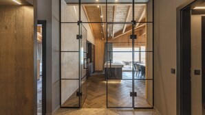 A modern interior with a wooden floor, a kitchen area, and a dining space visible through a glass partition.