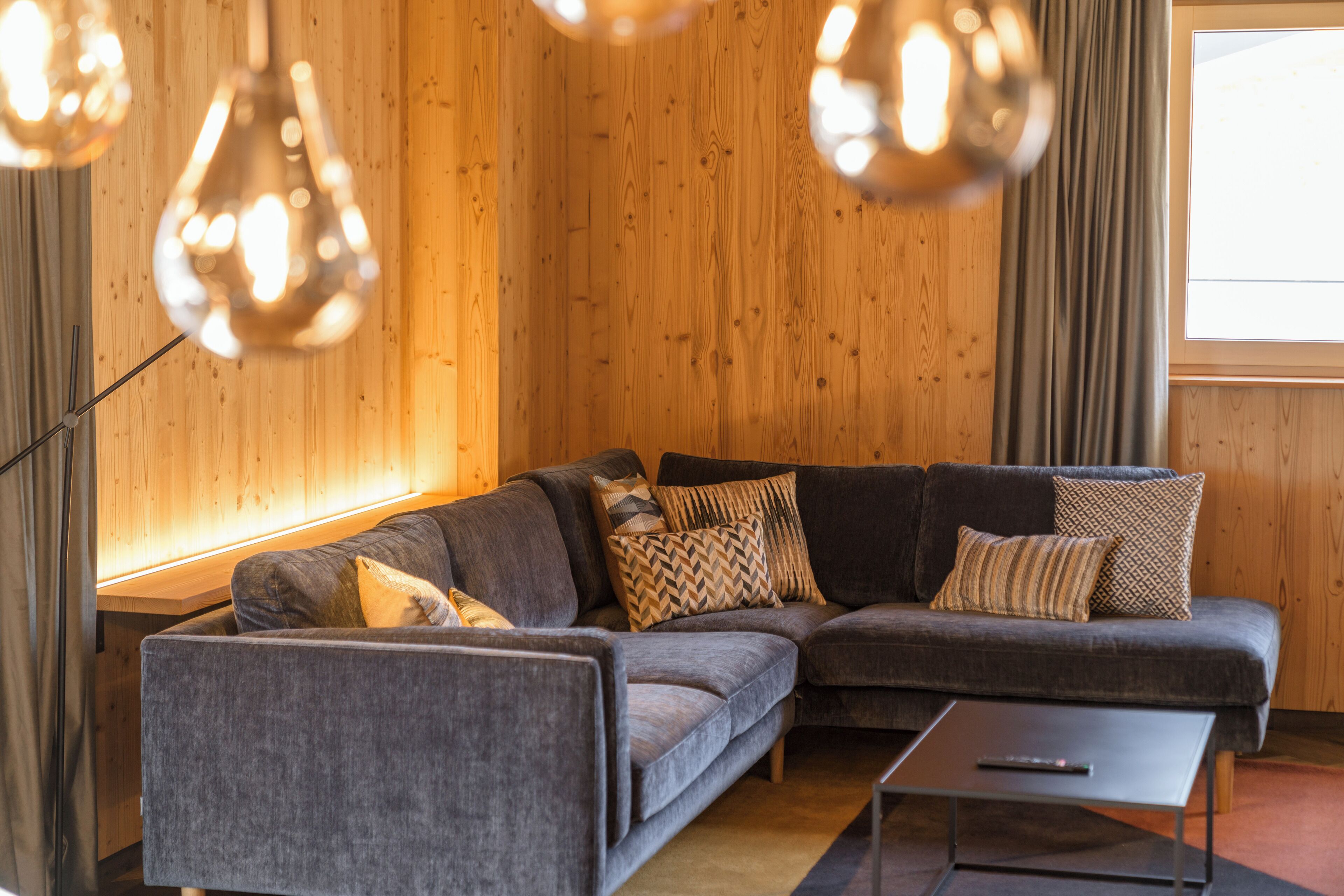 A modern living room with a grey sectional sofa, a floor lamp, and a window with curtains.