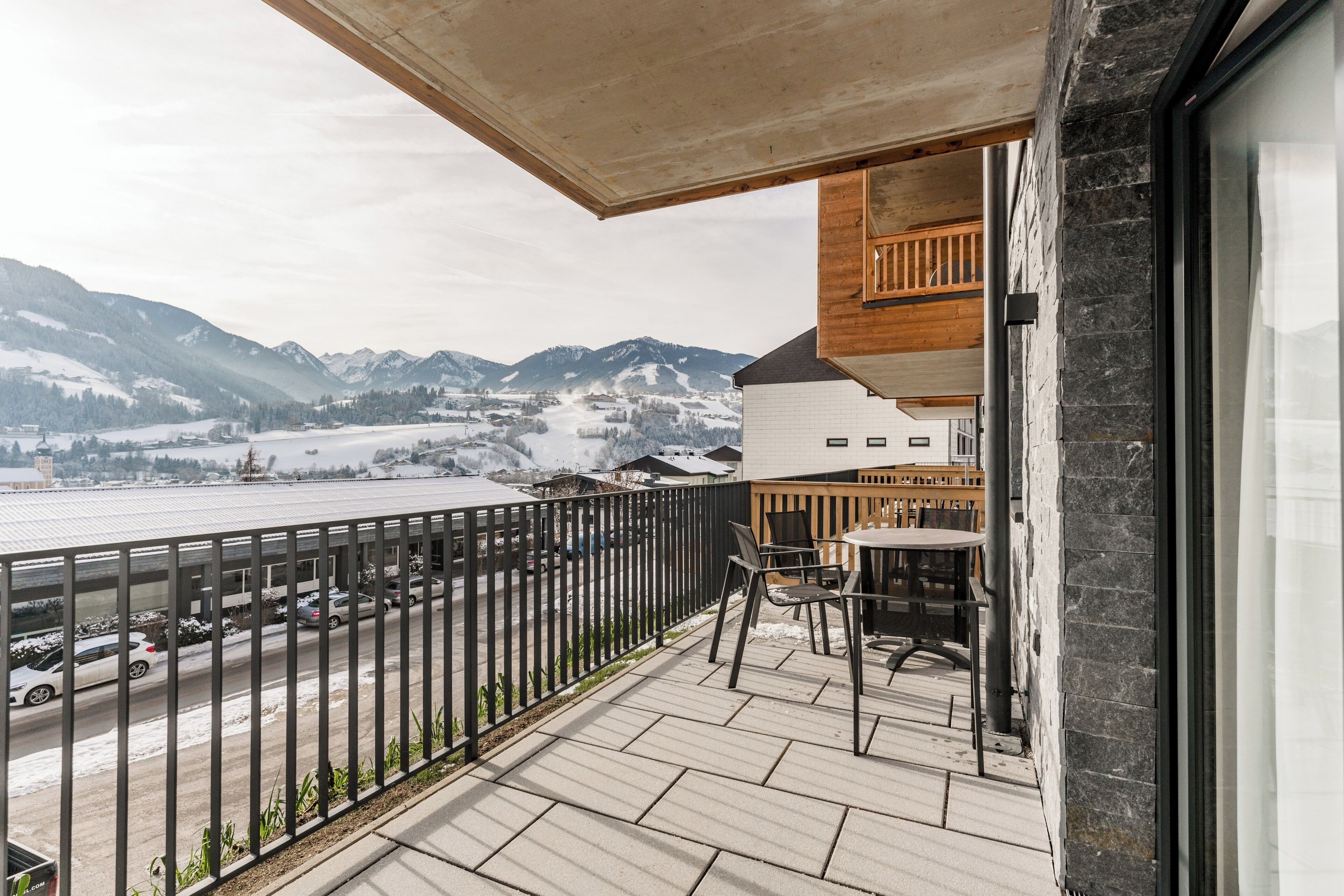 A balcony with a view of snow-covered mountains and a body of water.