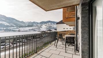 A balcony with a view of snow-covered mountains and a body of water.