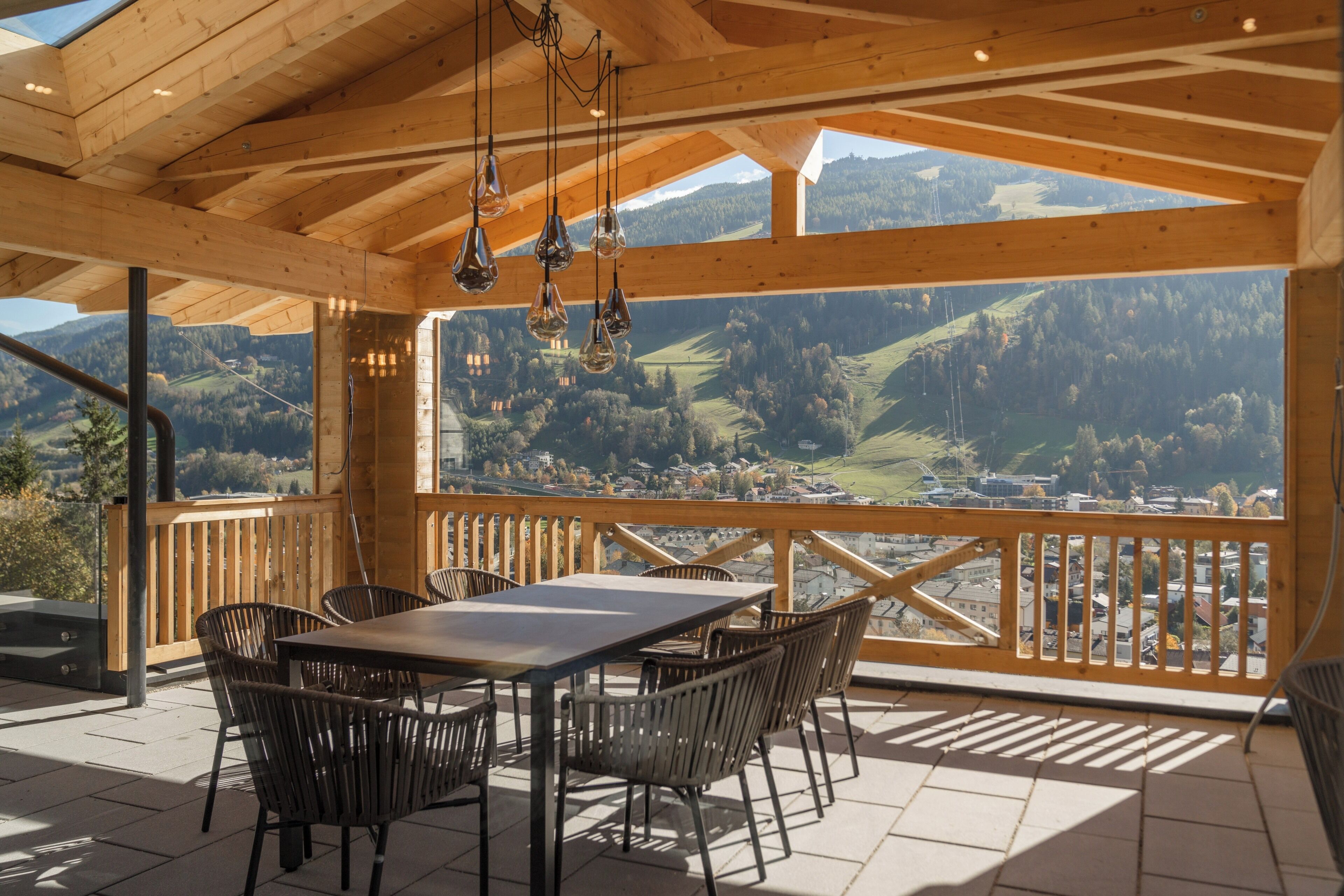 Eine Holzterrasse mit Tisch und Stühlen, mit Blick auf eine gebirgige Landschaft.