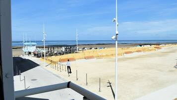 Une plage avec une tour de surveillance, des cabanes de plage et un ciel dégagé.
