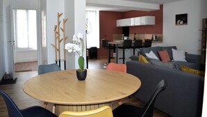 Una sala moderna con una mesa redonda de madera, un sofá gris y un comedor con sillas.
