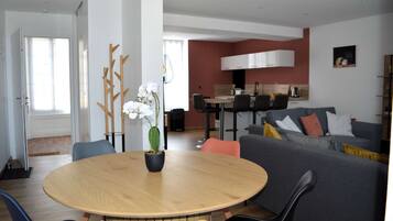 Un salon moderne avec une table ronde en bois, un canapé gris et un coin repas avec des chaises.