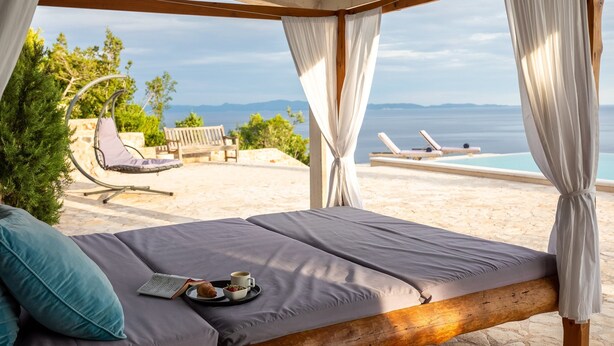 A bed with a view of the sea, a hanging chair, and a lounge chair by the pool. - Stone Houses Dingač (Orebic)