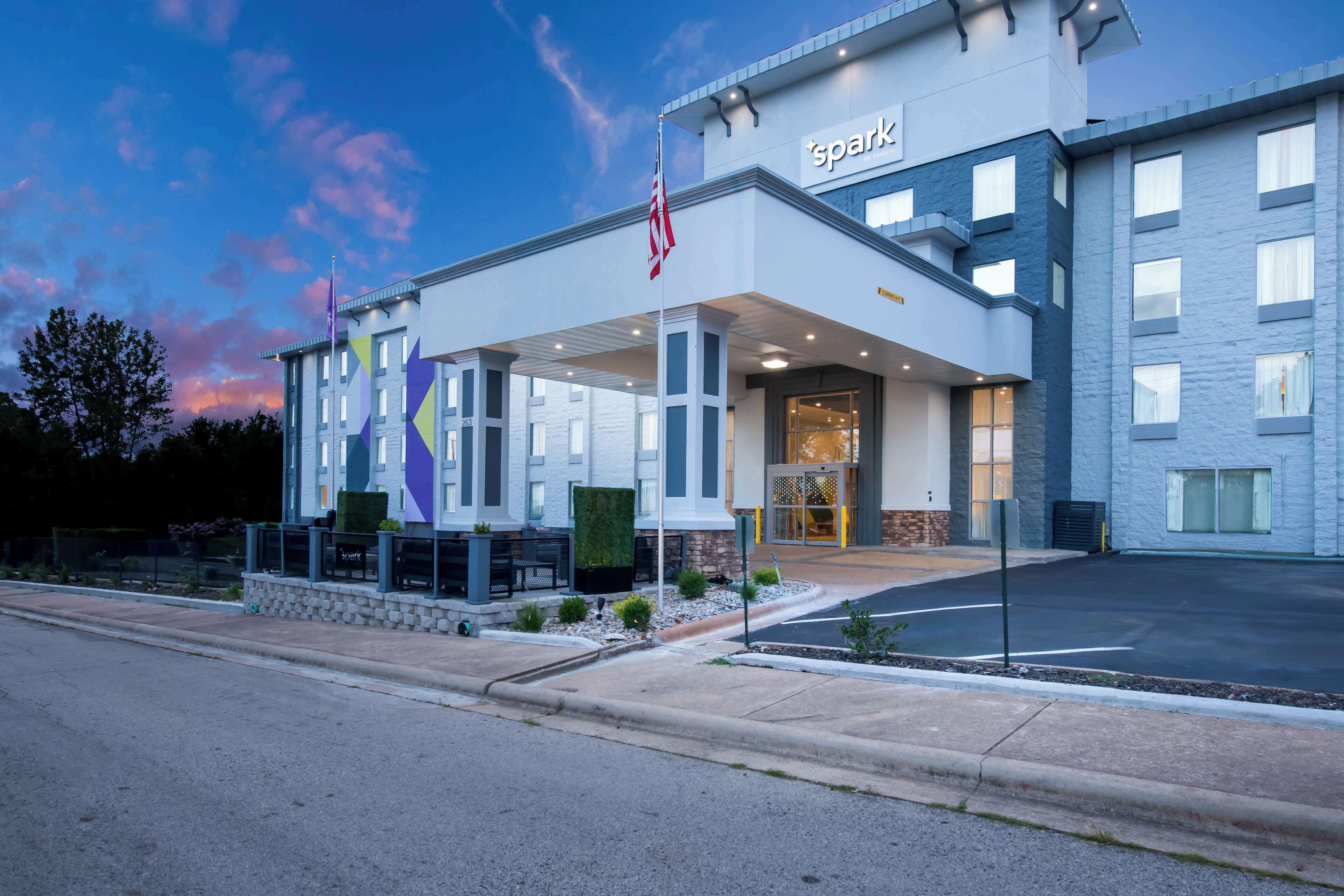 A hotel with a modern facade, a covered entrance, and an American flag.